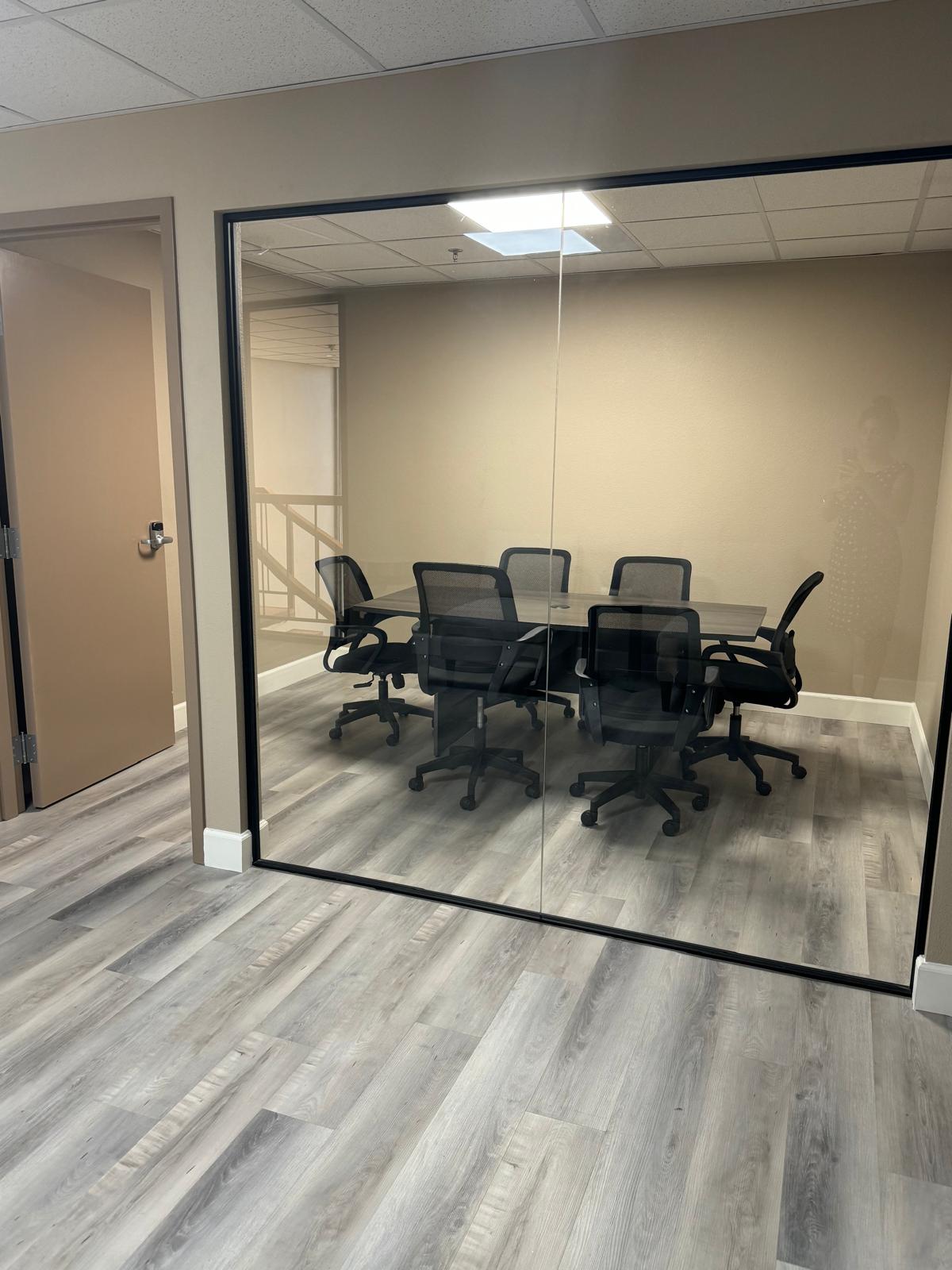 The Office conference room with a table and chairs behind glass walls